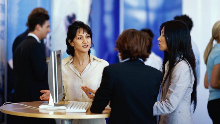 three businesswomen discussing services at an tradeshow exhibition