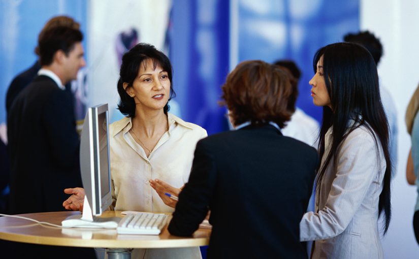 three businesswomen discussing services at an tradeshow exhibition